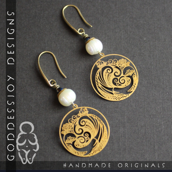 Earrings with brass whale filigree charms, topped with a glowing white cultured pearl, hanging from sleek smooth brass ear wires
